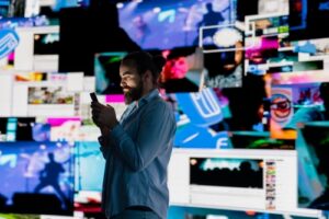 Man using a smartphone surrounded by digital media screens, illustrating social media evidence cases handled by Cincinnati criminal defense lawyers.